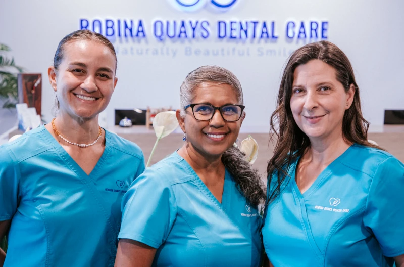 Three female team members smiling at the Robina Quays Dental Care reception