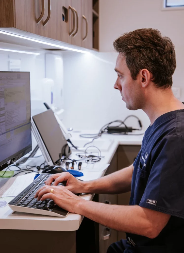 Robina Quays Dental Care clinician reviewing patient records at desktop computer