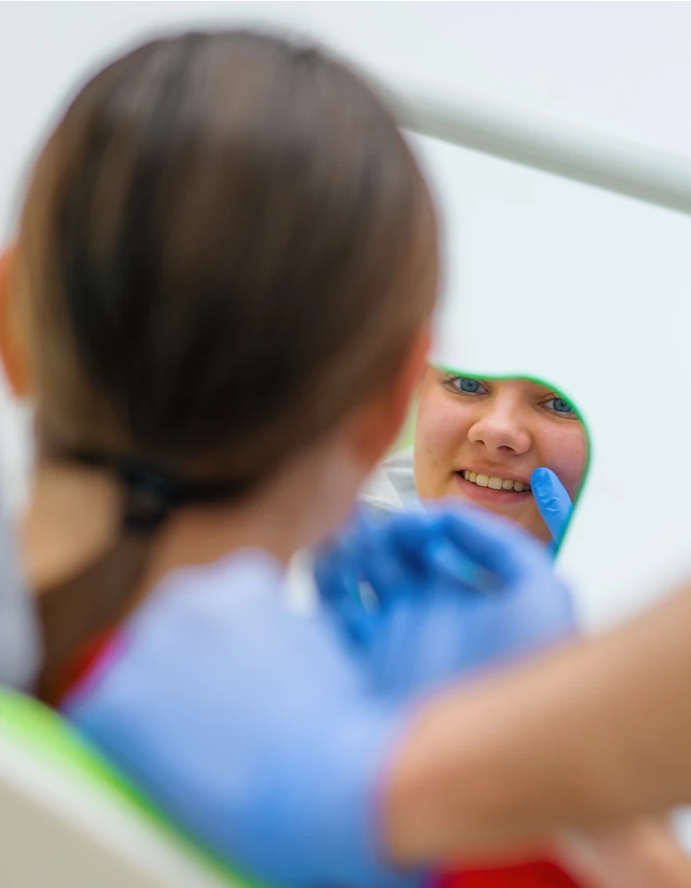 Female patient smiling in dental mirror after check-up at Robina Quays Dental Care